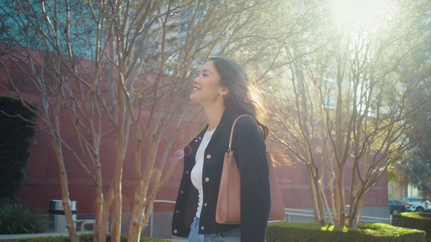 Attractive brunette have active leisure walking street on sunlight. Beautiful asian girl smiling going modern avenue near urban buildings. Confident woman exploring summer cityscape outdoors. 