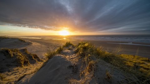 4k timelapse of stunning sunset on Dutch North sea coast with sand dunes and colouring clouds