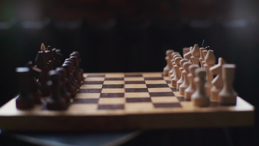 Close-up side view of black pieces making move first in chess game. Closeup of unrecognizable female hand makes first move in chess with black pawn. Concept of wrong start to business project. Royalty-Free Stock Footage #1086700808
