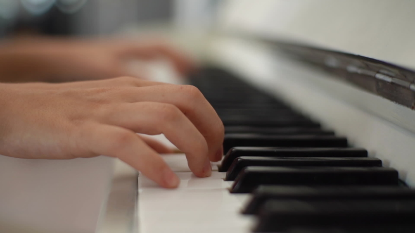 Extreme close-up hands of unrecognizable female pianist playing on classical piano calm gentle music during concert in light room. Closeup of lady student training to play piano in classrom.