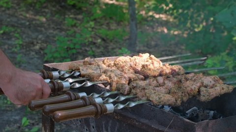 Shashlik barbecue. Kebab cooking outdoors on metal skewer. Marinated barbecue meat cooked at barbeque. Grilled pork, meat lamb, shish kebabs, shashlik. Street food popular in Europe, Russia