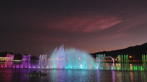 Spectacular fountain water dance show in Chiang Mai, Thailand on a late evening after sunset during twilight with background colorful sky and dark mountains