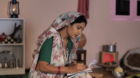 An attractive lady from an Indian village counting money - an Independent woman, monthly income, saving, financial literacy . A rural lady in traditional Saree holding two hundred and five hundred