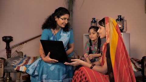 A government employee instructing a village lady for a government scheme - modern village family, government policy, insurance policy . A village woman in a traditional Sari and a sweet girl child