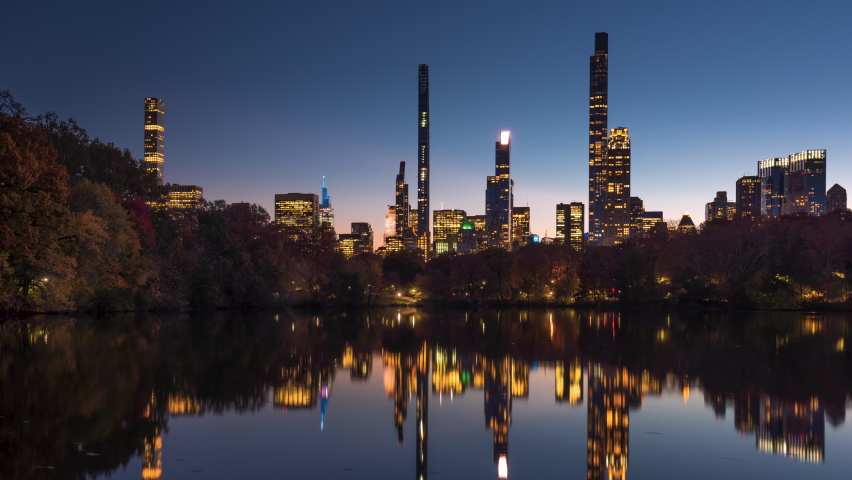 Central Park Lake with view of New York City Billionaire's Row from dusk to night. Timelapse citiscape of luxury apartment skyscrapers Royalty-Free Stock Footage #1086714440