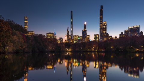 Central Park Lake with view of New York City Billionaire's Row from dusk to night. Timelapse citiscape of luxury apartment skyscrapers