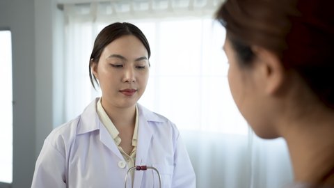 4k, An Asian female doctor wearing a white shirt is examining a female patient with a stethoscope in a hospital examination room. 10-Bit 4:2:2 50f
