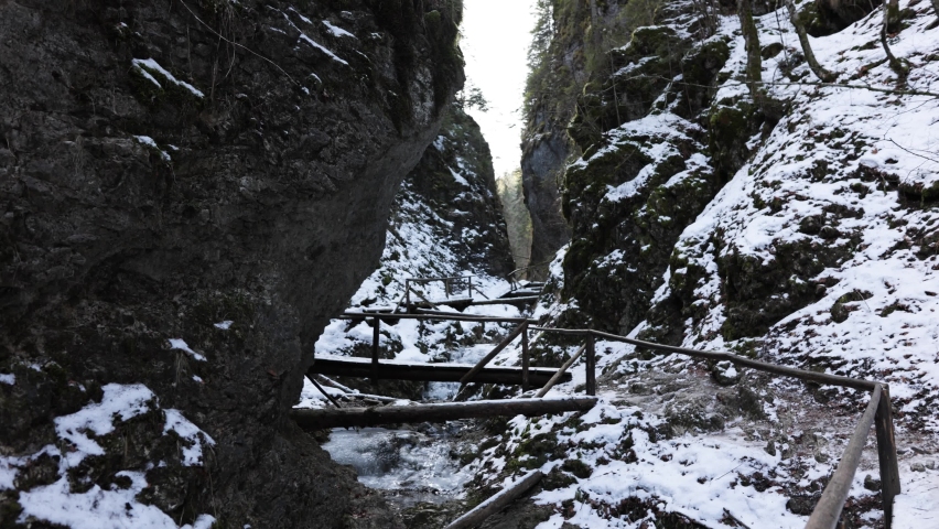 Wooden Bridge Between Rugged Cliffs Covered With Snow During Winter. Static Shot