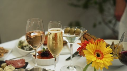 Glass of bubbly champagne with rose wine and martini on table full of food slow motion 4k 30p