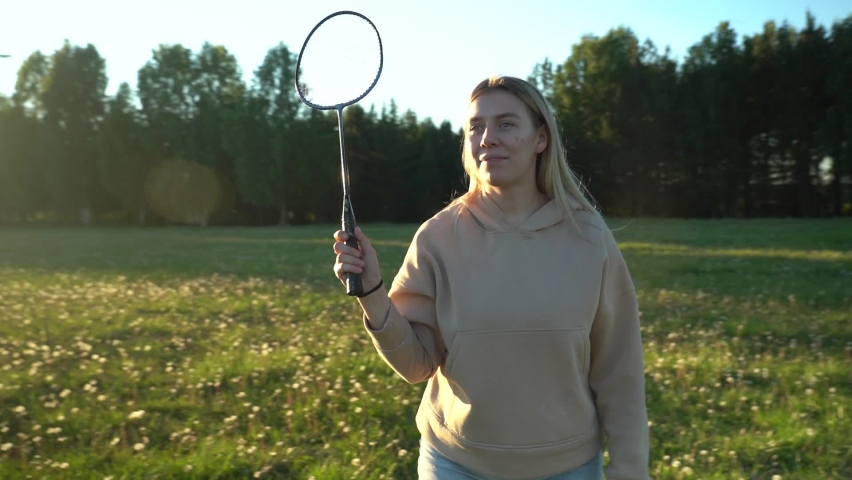 Young woman playing badminton, active games in summer in nature.