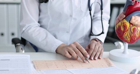 Cardiologist checks ecg cardiograph checks patient pulse closeup