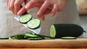 the cook cuts a spring salad of tomatoes, cucumbers, greens and mixes. Woman cutting cucumber for salad on wooden cutting board on kitchen table with cucumbers, tomatoes branch and scallion around. - Powered by Shutterstock - Get 15% off with code: PIKWIZARD15