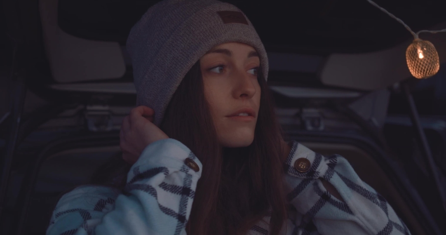 Attractive brunette girl, at dusk, lost in thought wearing a beanie hat.