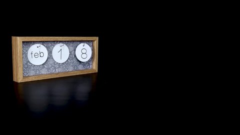 A wooden calendar block showing the date February 18th with a mans hand putting on and taking off the metal discs with the date and month on them, filmed in 8k quality 