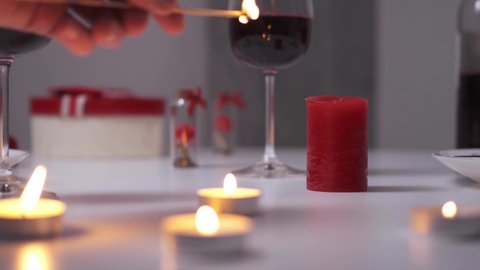 Lighting a candle. A man's hand lights candles with a stick. A romantic already lights a red candle. valentine's day romantic setting valentine's dinner
