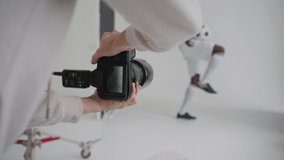 Photographer takes professional photos of a black football player in the studio on a white background
