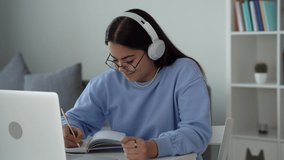 Happy teenage girl school pupil wearing headphones distance learning online at virtual lesson class with teacher tutor on laptop by video conference call studying at home. make pandiculation. 4k