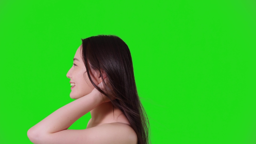 Young asian woman blowing her hair. Hair care concept. Green background for chroma key composition.