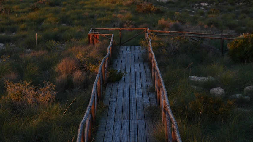 Adorable young girl running along a boardwalk to go to the beach in winter at sunset