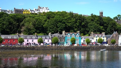 Beautifully coloured houses built on the promenade and on the hillside while the water gently lapping by on a sunny day. Wide shot.
