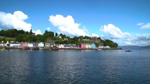 Small waves in calmly rippling water with the pretty coloured houses in the village of Mull on Tobermory Isle on a sunny day. Wide shot