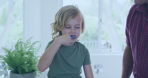 Video of handprints over caucasian boy brushing teeth. domestic life and quality family time together at home video.