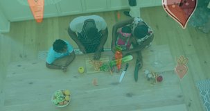 Animation of vegetables falling over african american family cooking together in the kitchen. family quality time, cooking and food concept digitally generated video.