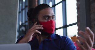 Video of digital interface over biracial man wearing face mask in restaurant. global networks, business and connections during covid 19 pandemic concept digitally generated video.