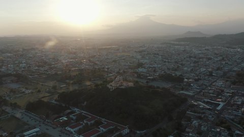 Circling the Great Pyramid of Cholula Church from extreme height in Cholula, Mexico at sunset.