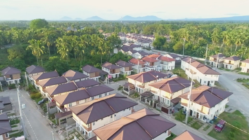Dolly-In Aerial Shot Of A Newly Built Village In Asia With Mountain Background View