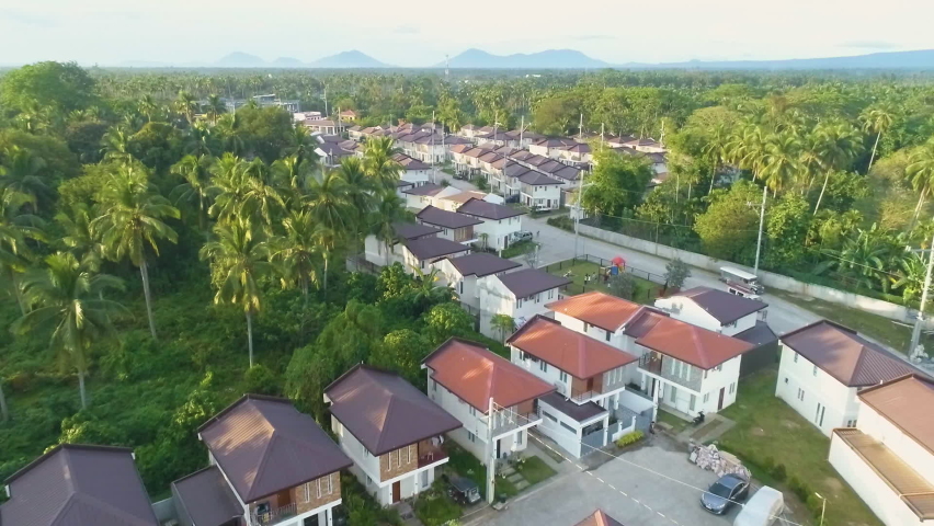 Dolly-Out Aerial Shot Of A Newly Built Village In Asia With Mountain Background View