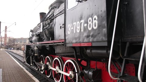 Vintage steam train locomotive, locomotive wheels. High quality. Steam train departs from railway station. Old vintage steam train on the rail road. Smoke covering. Close-up, detail, wheels