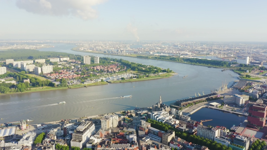 Inscription on video. Antwerp, Belgium. Flying over the roofs of the historic city. Schelde (Esco) river. Industrial area of the city. Glitch effect text, Aerial View