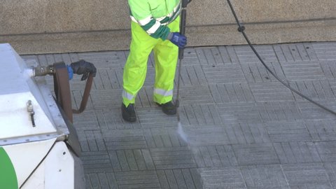 Sweeper cleaning a city sidewalk with high pressure washing machine. Real time video