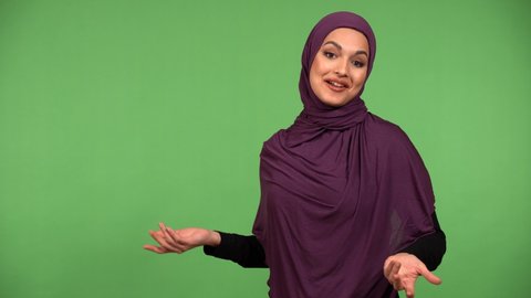 A young beautiful Muslim woman talks to the camera with a smile - green screen background