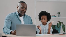 Happy mature african american caring father smiles helping little daughter schoolgirl with study homework chatting on webcam with tutor using laptop waving greeting online e-learning during quarantine
