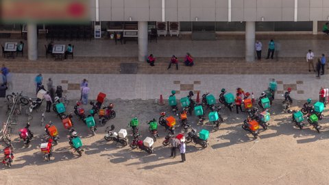 Many delivery motorcycles parked on the street near a restaurants and supermarket waiting for the order and delivery to the client. Aerial timelapse