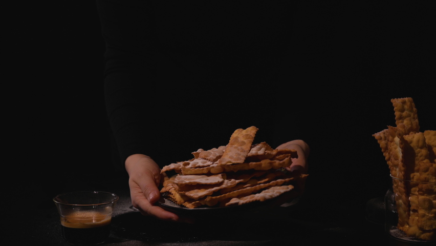 Carnival food TYPICAL and aromatic coffee.Sfrappole or chiachiere or angel wings. Traditional sweet crisp pastry deep-fried and sprinkled with powdered sugar.crispy dessert festive in female hands.4k