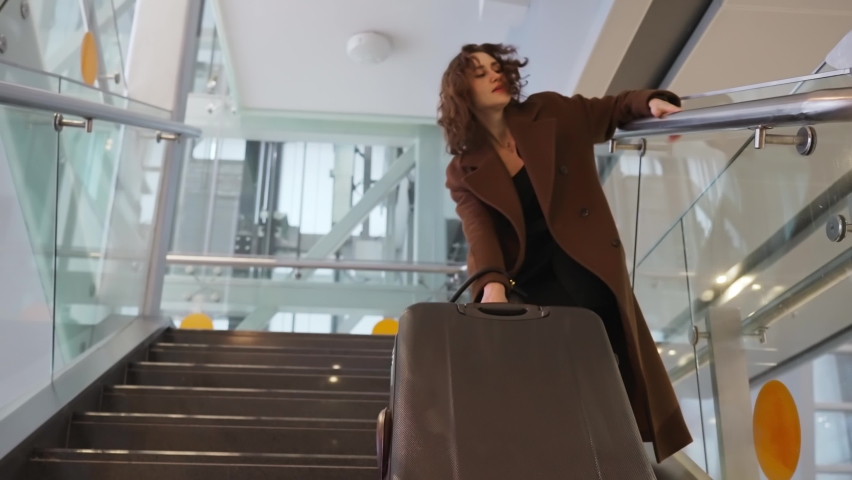 Slow motion footage of young elegant woman carrying heavy suitcase up the stairs at the airport. The concept of traveling with heavy luggage, being late for a flight High quality 4k footage Royalty-Free Stock Footage #1086769883