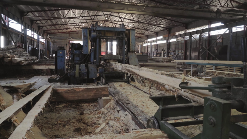 Automatic Log Saw Machine For Industrial Production Of Wooden Planks. Automatic Log Saw Machine At Woodworking Manufacturing Plant. Automatic Log Saw Machine Produces Material For Boards Making