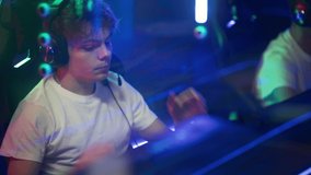 Player Removes Audio Headset And Concentrates After Video Game Round At E-Sports Arena. Teenage Boy Playing Video Games At Competitive Cyber Sport Arena. Gamer Playing On Modern PC At Video Game Arena