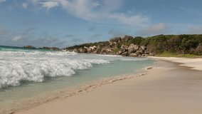 A peaceful and relaxing scene of a tropical beach, waves and blue sky. 
A video captures, turquoise water of Indian Ocean, rock boulders and waves crashing on a white sand beach in La Digue island, Se