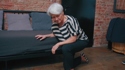 caucasian grey-haired senior woman falling down the sofa supported by her surprised middle-aged son. High quality photo