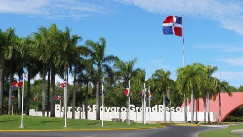 PUNTA CANA, DOMINICAN REPUBLIC - February 5, 2022: Barcelo Bavaro Grand Resort entrance facade in Punta Cana. Traditional caribbean gate and fence, decorated coconut palms and national flags