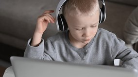 Caucasian Boy in headphones watching a video lesson at a computer. 4K