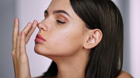 Beautiful girl touches her nose and thinks about rhinoplasty. Dream of plastic surgery