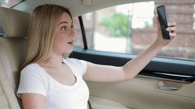 a woman is talking on a mobile phone on a video call, solving questions or having a friendly conversation while riding in a taxi.