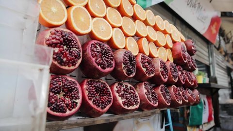 Sliced ripe fruits in street food store. Cutting fresh pomegranate and oranges in grand bazaar. Delicious exotic fruits in Turkish market in Tel Aviv, Israel