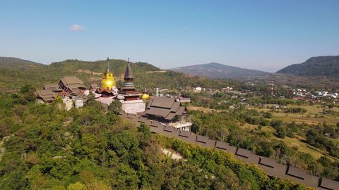 Aerial footage sliding to the right revealing the famous Wat Somdet Phu Ruea, the village of Ming Mueang and farmlands, Loei in Thailand.