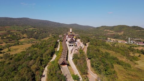 Aerial footage towards the famous temple from and high altitude revealing a car moving on the right and the roof of the complex, Wat Somdet Phu Ruea, Ming Mueang, Loei in Thailand.